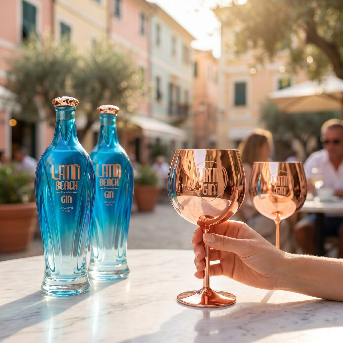 Raising a rose gold Copa cup beside two bottles of Latin Beach gin in an Italian piazza
